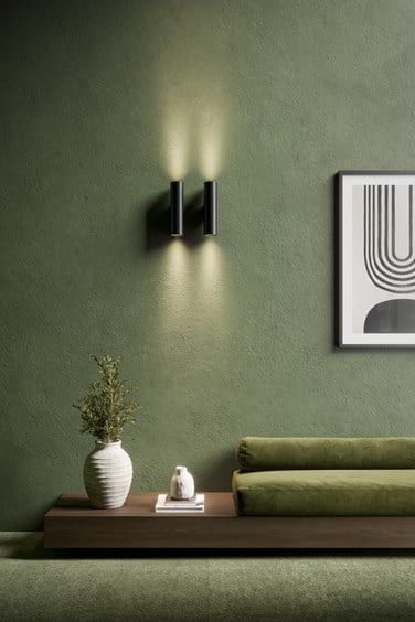 Black cylinder lights on a green living room wall that inspires earthy and natural feeling